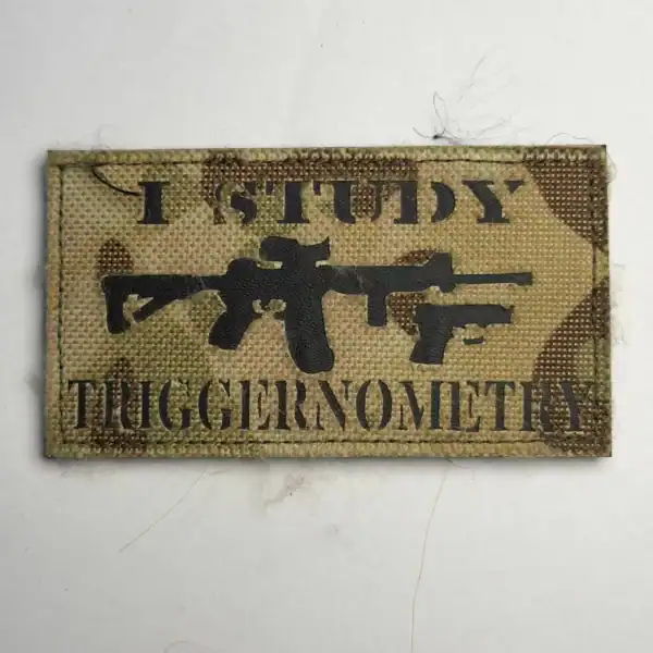 Russian trophy gear patch with firearm silhouettes and English combat slogan on camouflage fabric