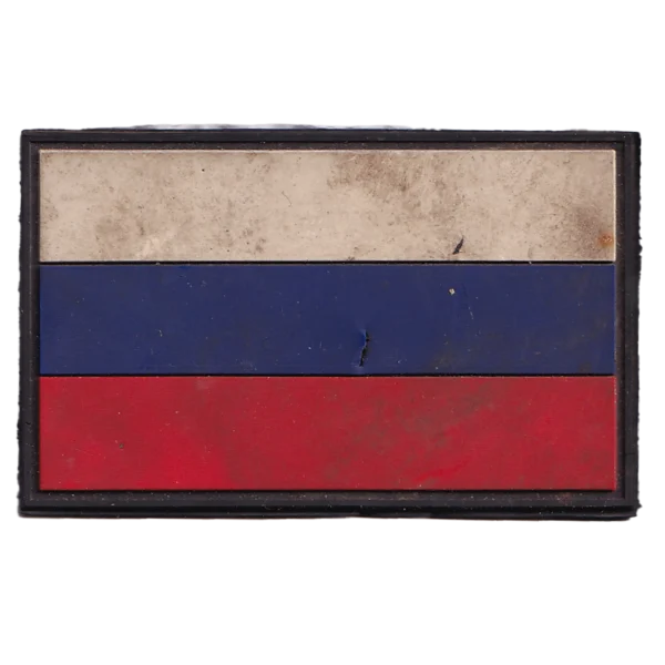 Russian Shrapnel Damaged Flag Patch in white, blue, and red PVC with visible impact puncture, field wear, black border, and hook-and-loop backing.
