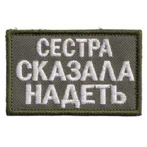 Home 23 Russian Sister Told Me Patch with white Cyrillic text embroidered on olive fabric, green border, and hook-and-loop backing.