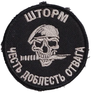 Home 23 Russian Storm Z Patch with skull in combat helmet, white embroidered “Storm” and “Here are valor and honor” text, black field, and trophy provenance from Ukraine.