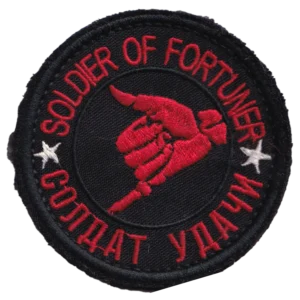 Home 25 Russian Soldier of Fortune Patch with bilingual red lettering, white stars, a dagger held in a clenched hand, black fabric, and hook-and-loop backing.